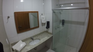 A bathroom with a sink, mirror, towel rack, and a glass-enclosed shower.