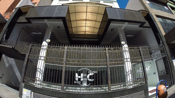 A hotel entrance with a modern design, featuring a glass facade and a metal gate.