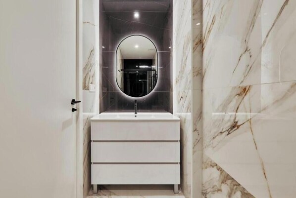 A bathroom with a marble vanity, a round mirror, and a modern sink. - Spacious Group Apartment in the Heart of Madrid Near Plaza Mayor (Madrid)