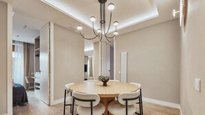 A dining area with a round table, four chairs, a chandelier, and a view into another room. - Spacious Group Apartment in the Heart of Madrid Near Plaza Mayor (Madrid)