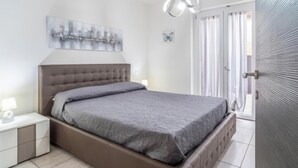 A bedroom with a bed, nightstands, a wall-mounted artwork, a ceiling light, and a door with a textured wall. - Lara Residence - Agropoli (Agropoli)