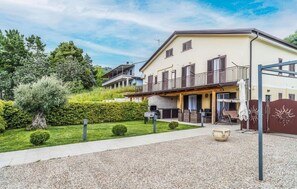 Una casa a due piani con un balcone, un patio con posti a sedere all'aperto e un giardino curato.
