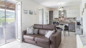 A modern living room with a brown leather sofa, a dining area with a striped table, and a kitchen with patterned tiles. - Lara Residence - Agropoli (Agropoli)