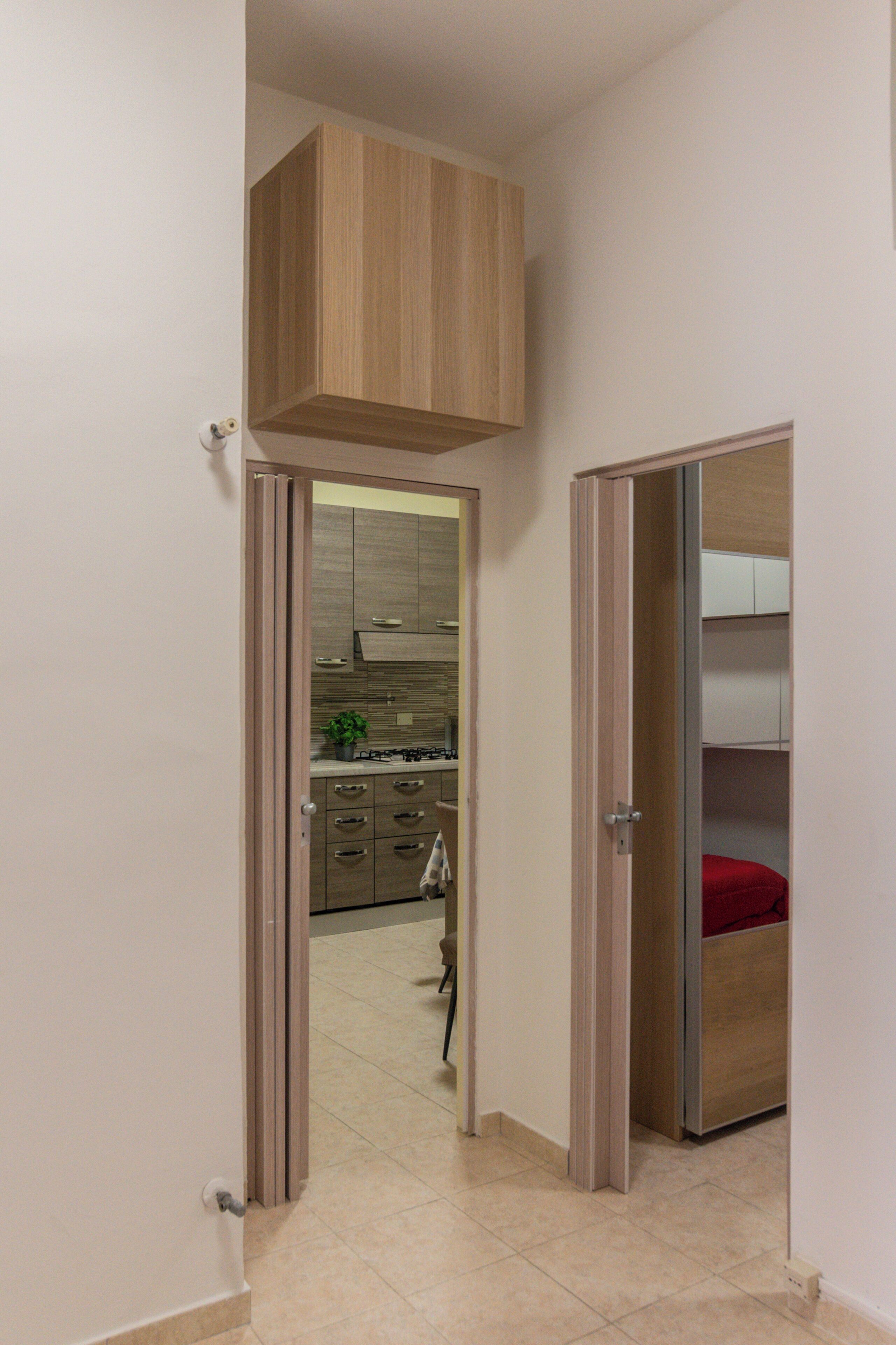 Ein schmaler Gang mit einem Holzschrank und einem roten Gegenstand auf einem Regal.