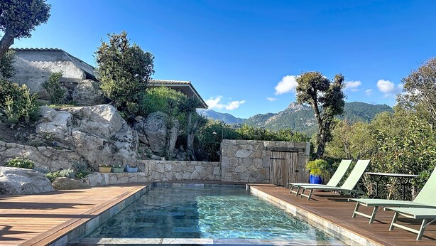 A wooden deck with a swimming pool, lounge chairs, and a stone wall with a wooden door. - Exceptional sheepfold with heated pool, close to amenities (Sotta)