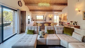 A modern living room with a large sectional sofa, a dining area with a bar, and a kitchen in the background. - Exceptional sheepfold with heated pool, close to amenities (Sotta)
