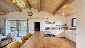 A modern kitchen with a wooden table, yellow chairs, and a clock on the wall. - Exceptional sheepfold with heated pool, close to amenities (Sotta)