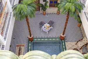 Una terraza en la azotea con palmeras, una mesa de comedor con comida y un suelo estampado.