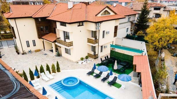 A hotel with a rooftop pool, lounge chairs, and a covered outdoor area. - family hotel BONJOUR (Panagyurishte)