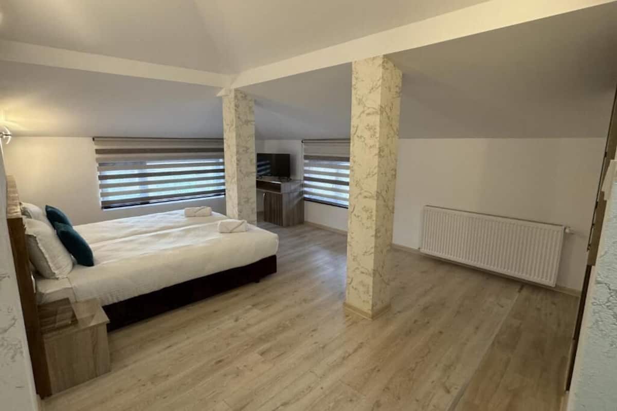 A bedroom with a bed, a desk, and a radiator.