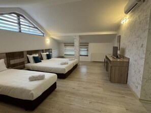 A bedroom with three beds, a desk, and a radiator. - family hotel BONJOUR (Panagyurishte)