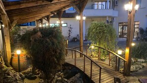 A wooden bridge over a rocky area with a tree and a barrel. - family hotel BONJOUR (Panagyurishte)