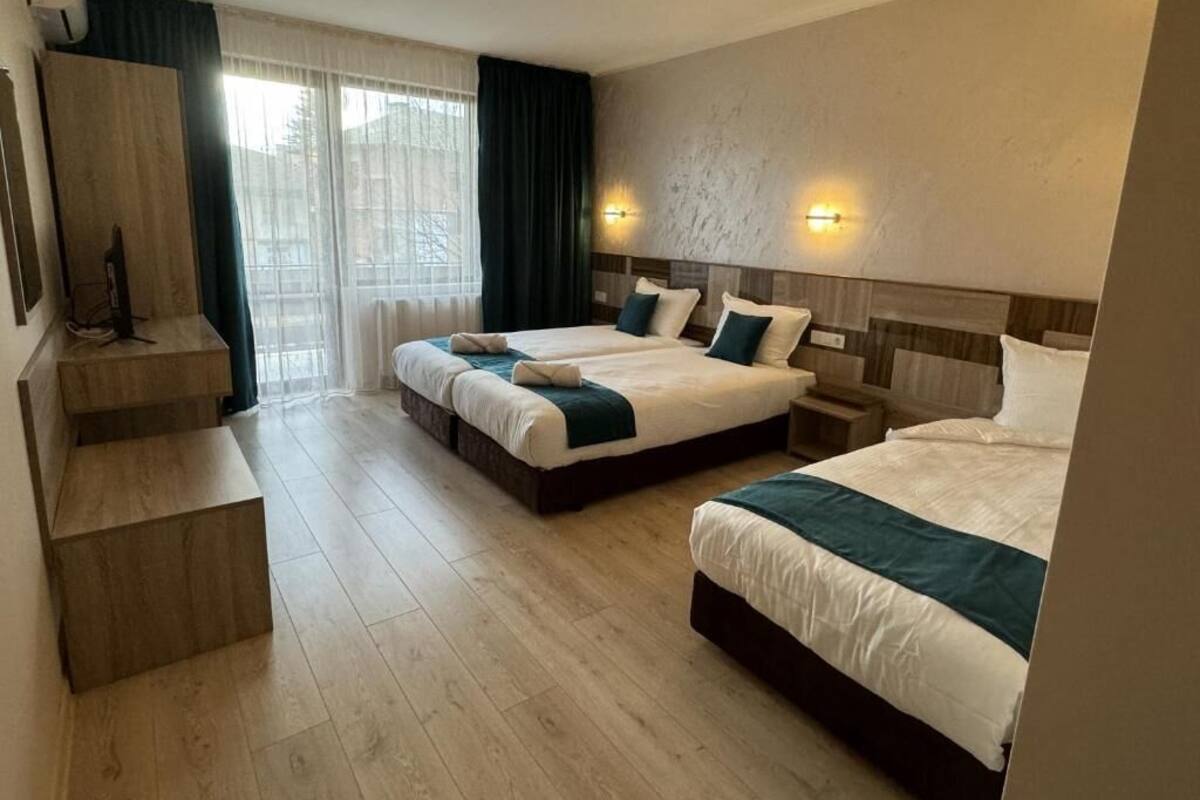A hotel room with three beds, a flat-screen TV, and a staircase.