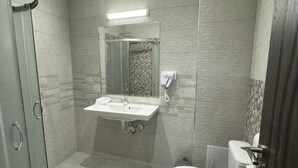 A bathroom with a glass shower enclosure, a sink with a mirror, and a toilet. - family hotel BONJOUR (Panagyurishte)