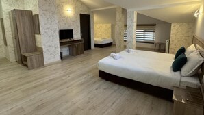 A bedroom with a large bed, a TV, a desk, and a bathroom. - family hotel BONJOUR (Panagyurishte)