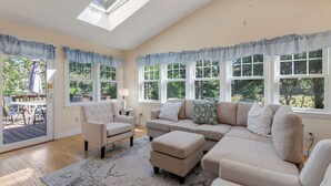 Un salon comprenant un canapé, des fauteuils, un tapis et un coin repas avec une table et des chaises.