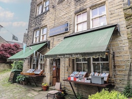 A bookstore with a green awning, a signboard, and books displayed outside.