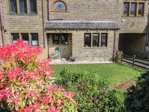 A stone building with a small front yard, a door, and a window with shutters. - Underview (Holmfirth)