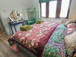 Un dormitorio con cama, escritorio, espejo y ventana.