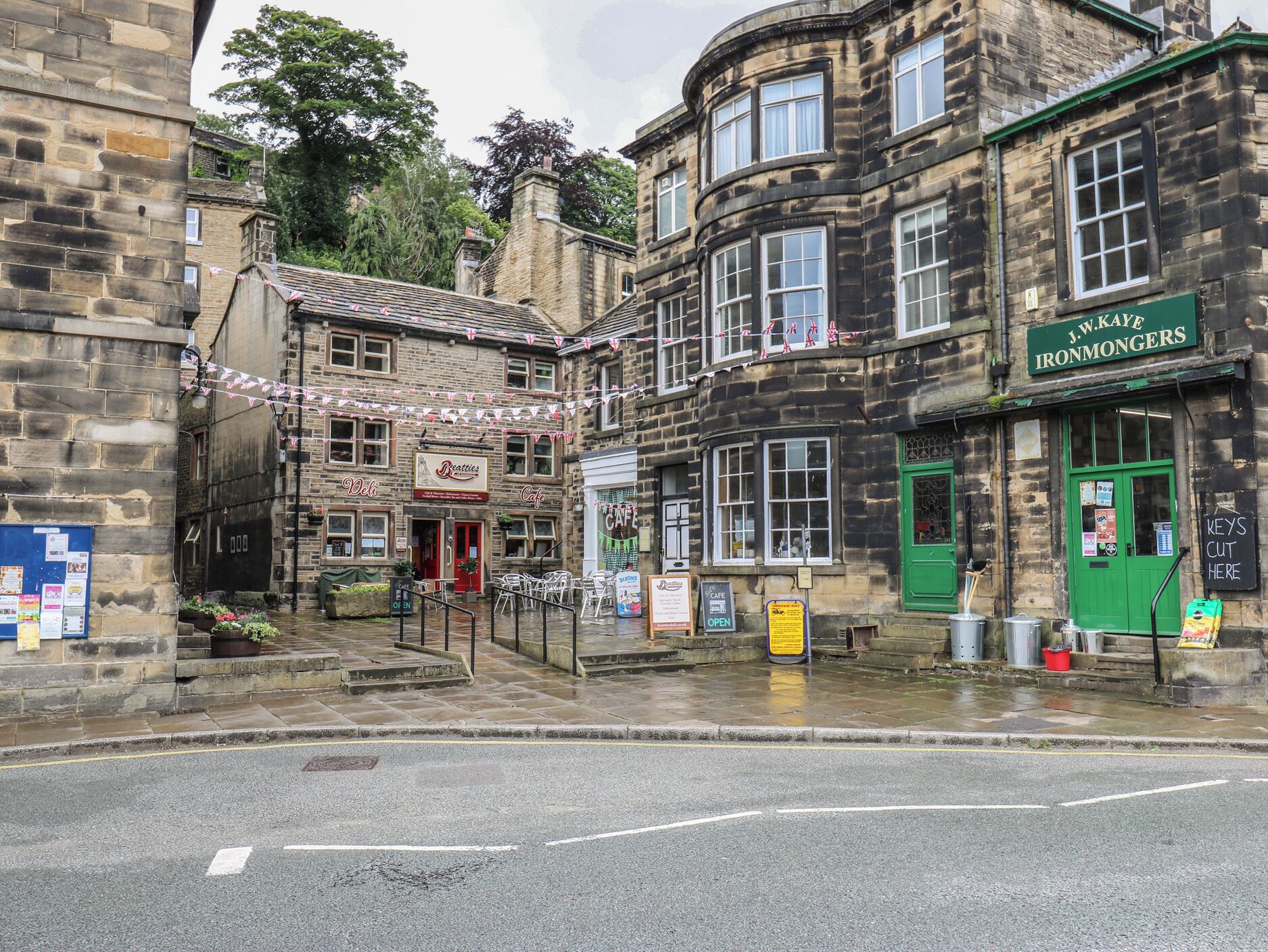 A street with buildings, including a cafe and a shop with a green door.