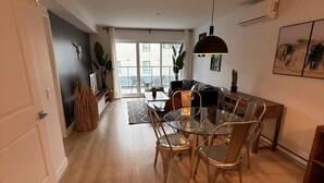 A modern apartment with a dining area, a living room, and a balcony with a view.