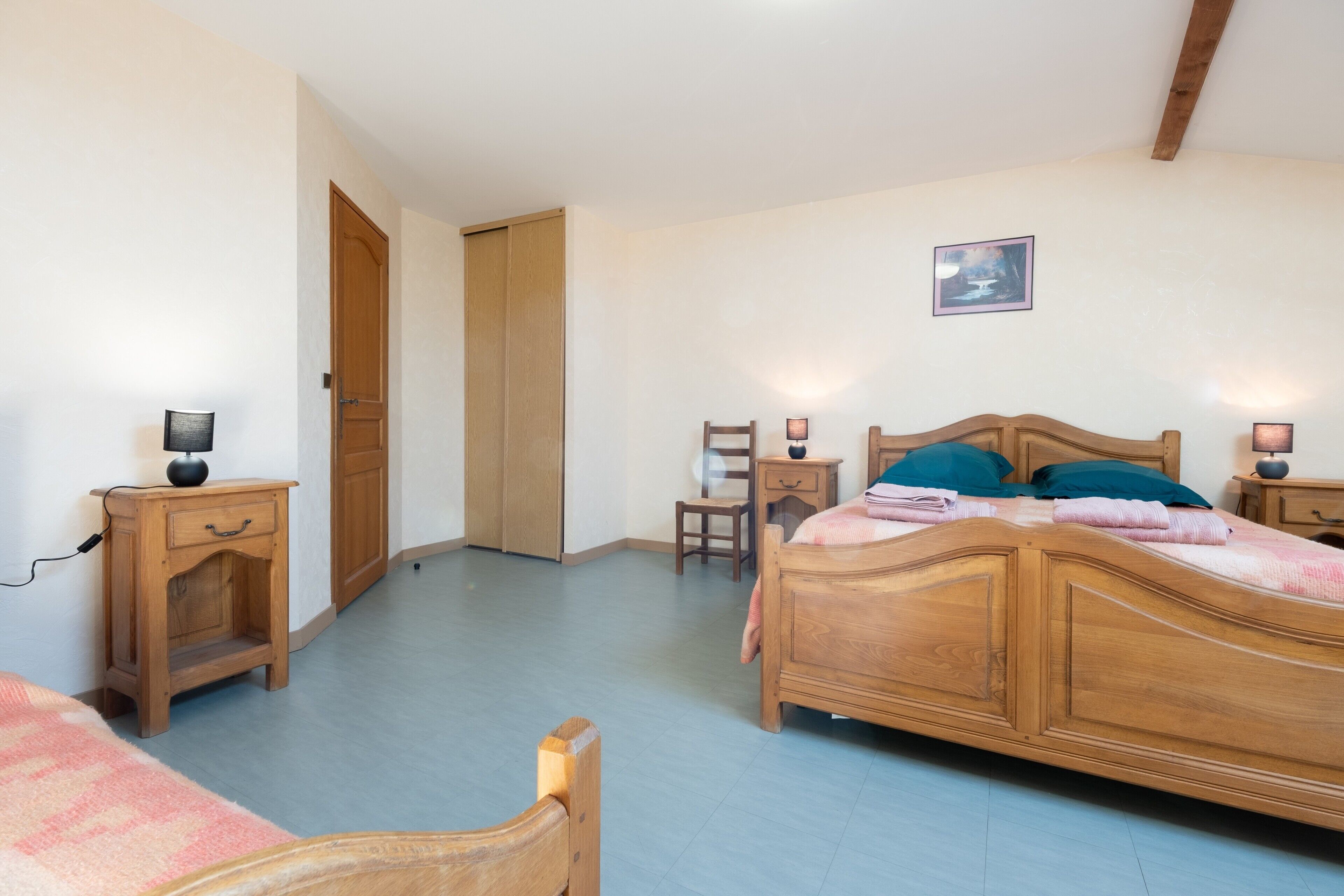 A bedroom with a wooden bed, bedside tables, a chair, and a door.