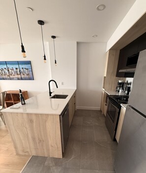 A modern kitchen with a central island, stainless steel appliances, and pendant lighting.