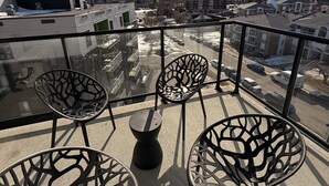 Ein Balkon mit vier Stühlen und einem Tisch, mit Blick auf eine Wohngegend.