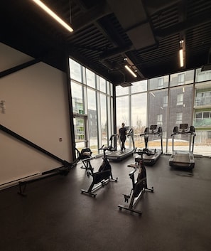 A gym with stationary bikes, treadmills, and a person exercising.