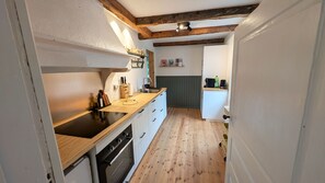 A narrow kitchen with wooden flooring, a built-in oven, and a sink. - Idyllic and family friendly cottage in Småland | SE06095 (Ryssby)