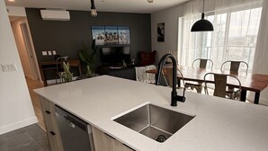 A modern kitchen with a central island, built-in dishwasher, and pendant lighting. - Modern 1BD Suite at Le Prisme w/ Private Balcony, Pool, Gym & Yoga Studio (Québec)