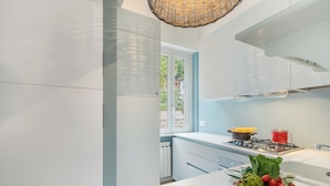 A modern kitchen with white cabinets, a gas stove, and a window overlooking greenery. - Kenyon Charm - Total Sea View (Alassio)