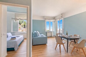 Un dormitorio moderno con una cama, un sofá azul y una zona de comedor con mesa y sillas.