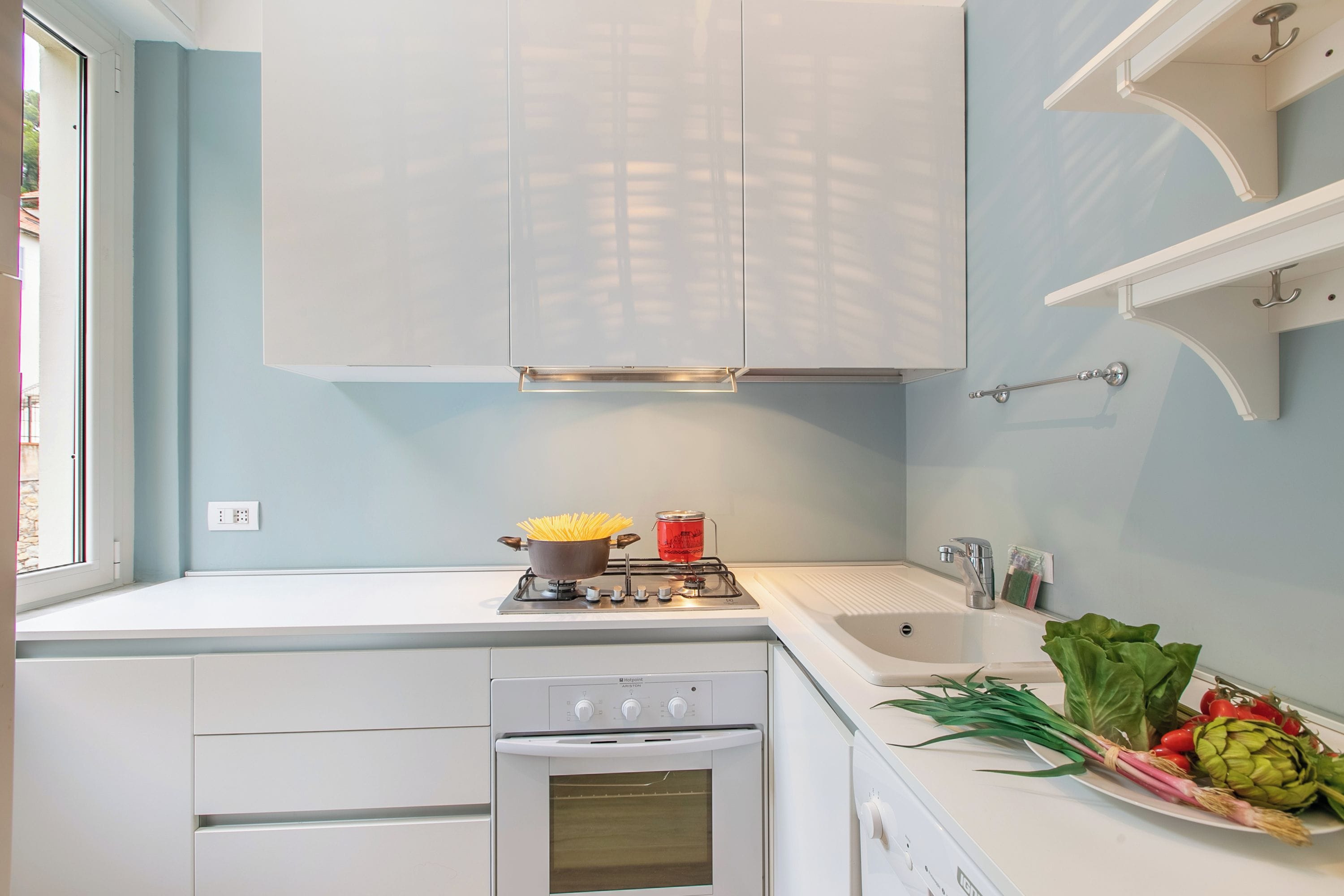 A kitchen with white cabinets, a stove, oven, and a sink.