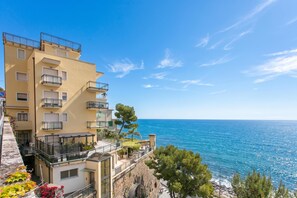A coastal building with balconies overlooking the sea, a stone wall, and a clear sky. - Kenyon Charm - Total Sea View (Alassio)