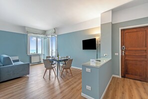 A modern living room with a sofa, dining table, chairs, a TV, and a wooden door.