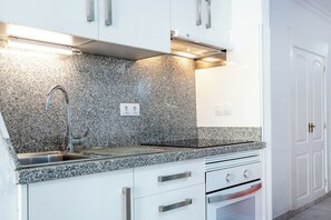 A kitchen with granite countertops, stainless steel sink, white cabinets, and a built-in oven. - Great Location Santa Maria Studio . Pool view.Fully refurbished.Air con. WIFI (Costa Adeje)
