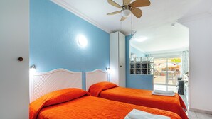Hotellihuone, jossa on kaksi sänkyä, kattotuuletin ja näkymä ulos.