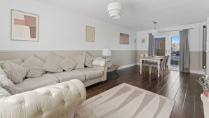 Ein Wohnzimmer mit einer Couch, einem Esstisch und einer Lampe.