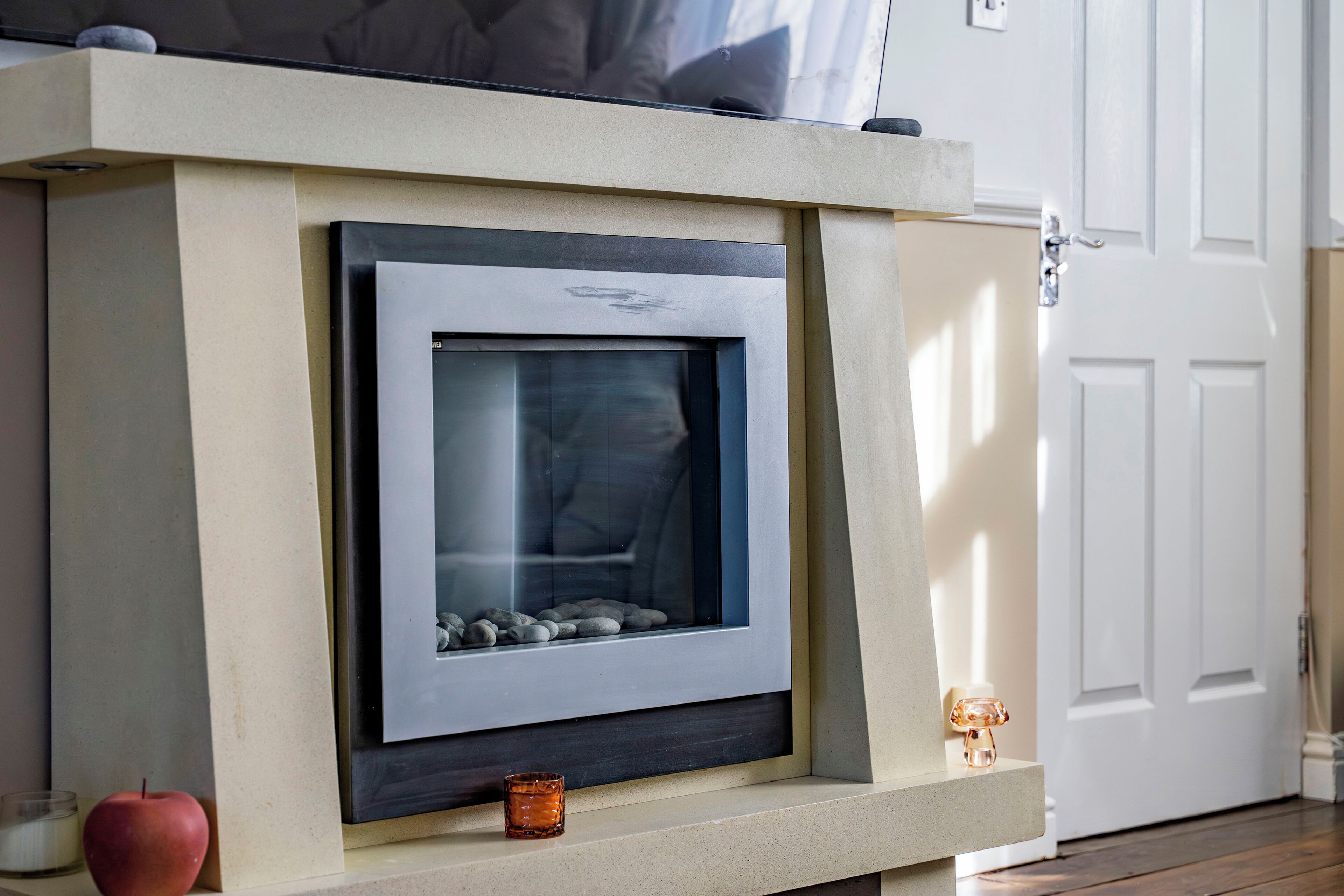 A fireplace with a stone surround, a framed picture above it, and a small candle on the mantel.