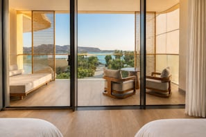 Un balcon avec vue sur un plan d’eau, un coin salon avec une table et un lit.