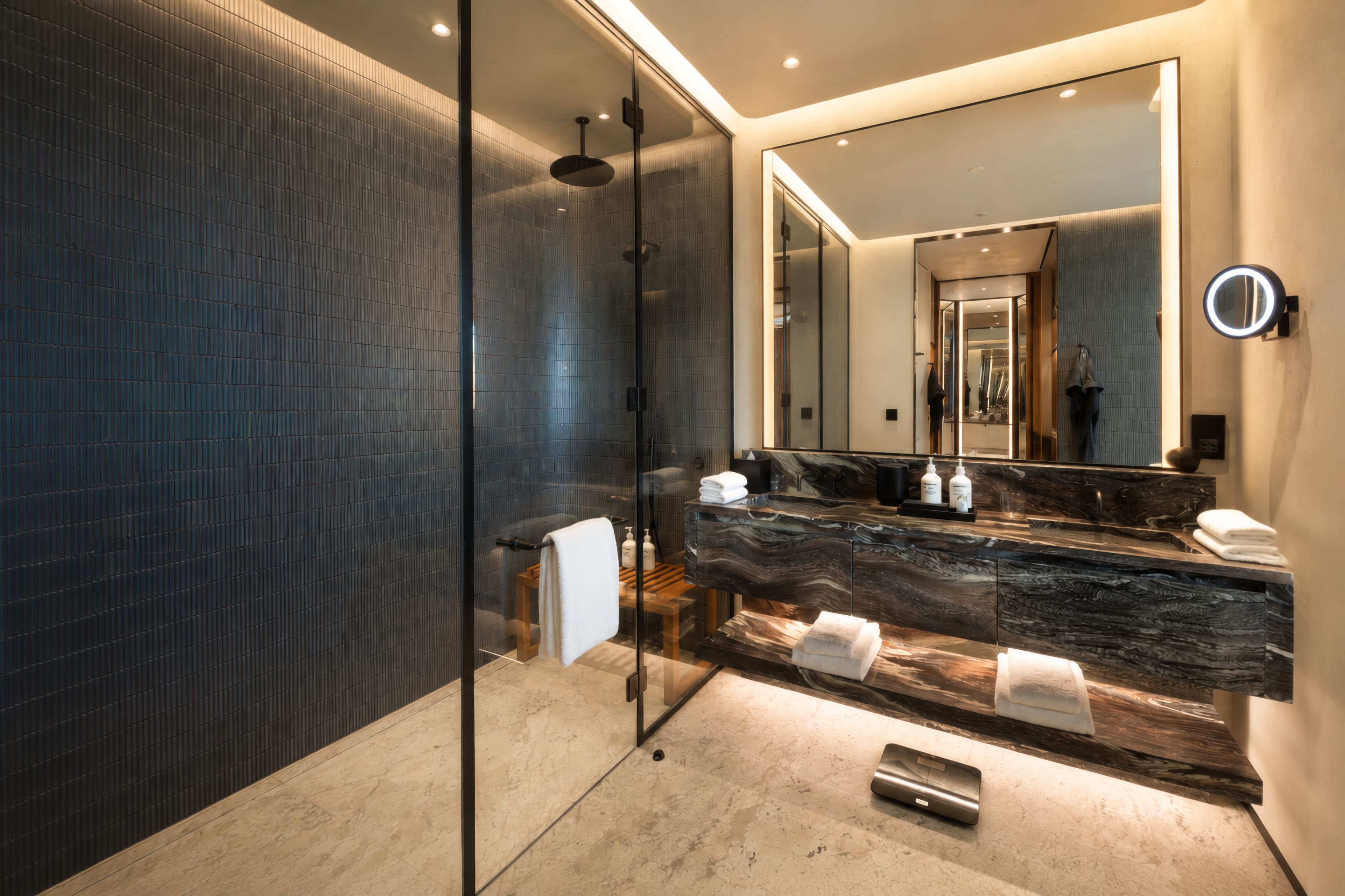 Een moderne badkamer met een douchecabine van glas, een marmeren wastafel en een grote spiegel.