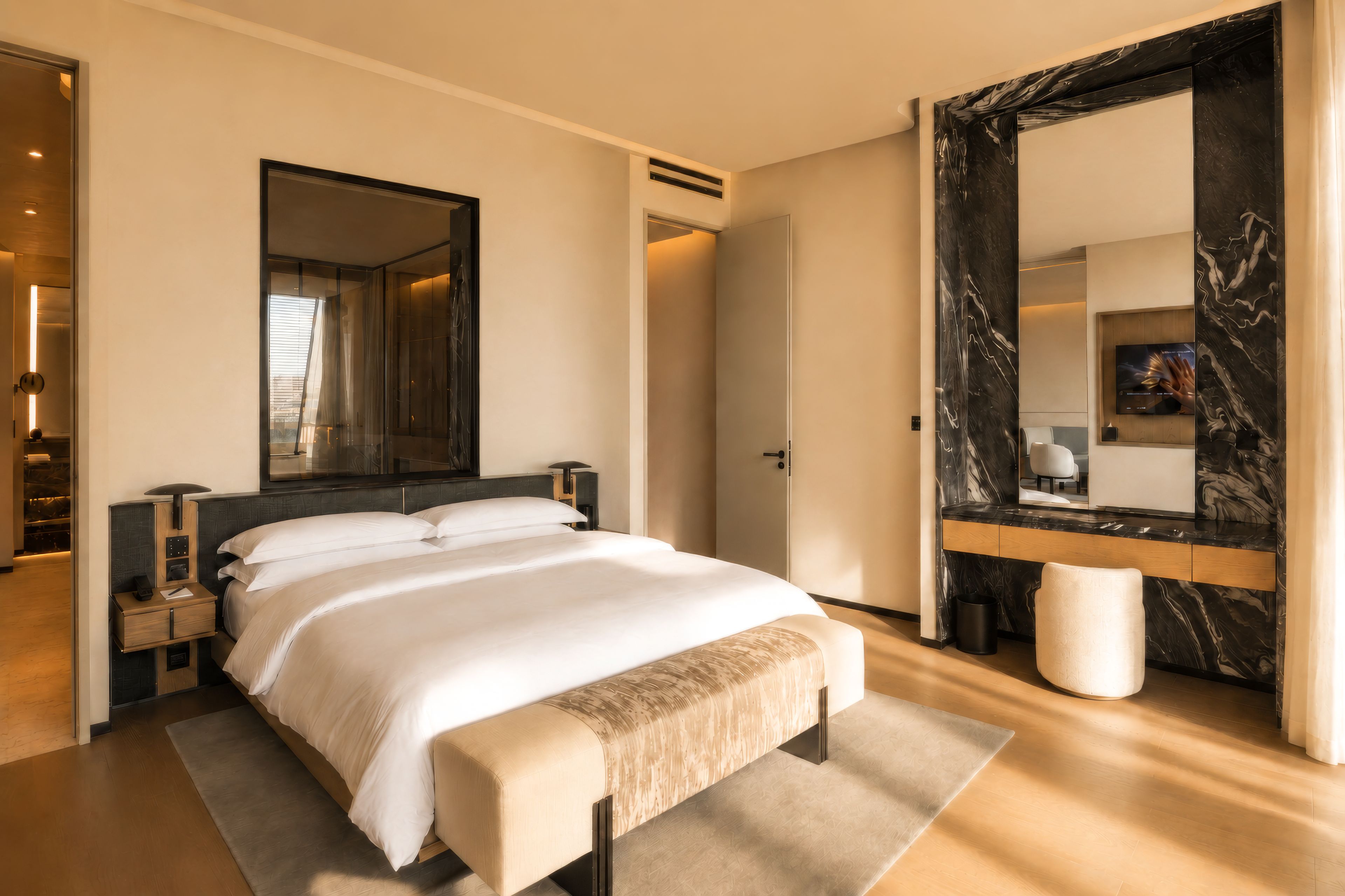 A modern bedroom with a large bed, a mirror, and a wooden bench.