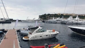 Un puerto deportivo con varias embarcaciones amarradas, incluyendo un yate blanco y un bote inflable rojo.