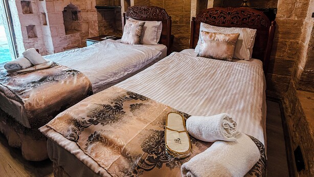 A room with two beds, stone walls, and a window. - DARA KONAĞI (Mardin)