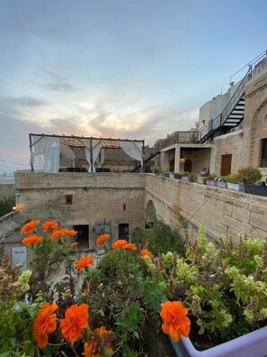 A rooftop terrace with a pergola, potted plants, and a stone building with arches. - DARA KONAĞI (Mardin)
