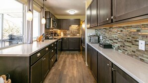 Una cocina moderna con armarios oscuros, una isla central y un protector contra salpicaduras de piedra.