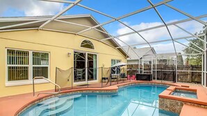 Ein Schwimmbad mit Glasverkleidung, eine überdachte Terrasse und ein gelbes Gebäude mit vergitterten Fenstern.