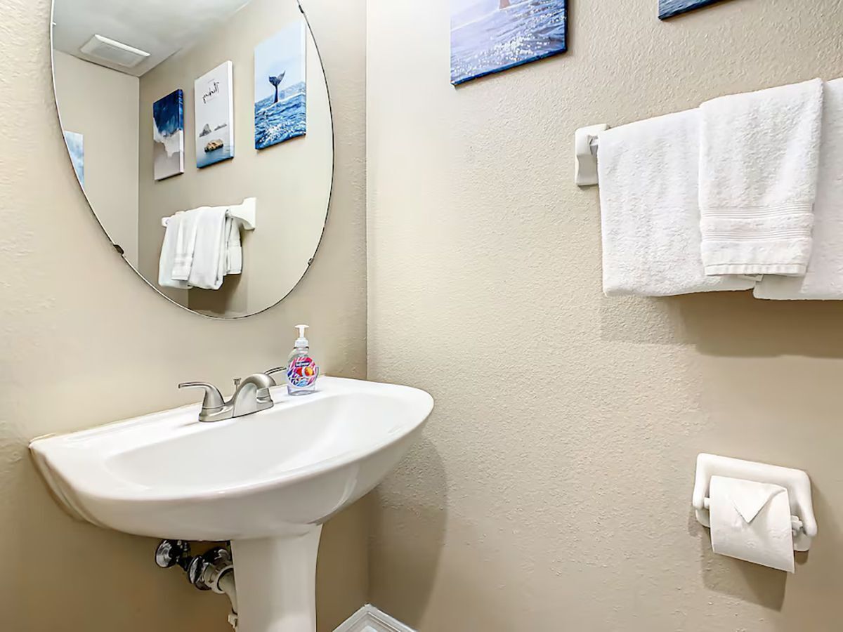 A bathroom with a sink, mirror, and towel rack.