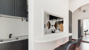 Una cocina moderna con armarios oscuros, una encimera blanca y un estante empotrado con espejo.